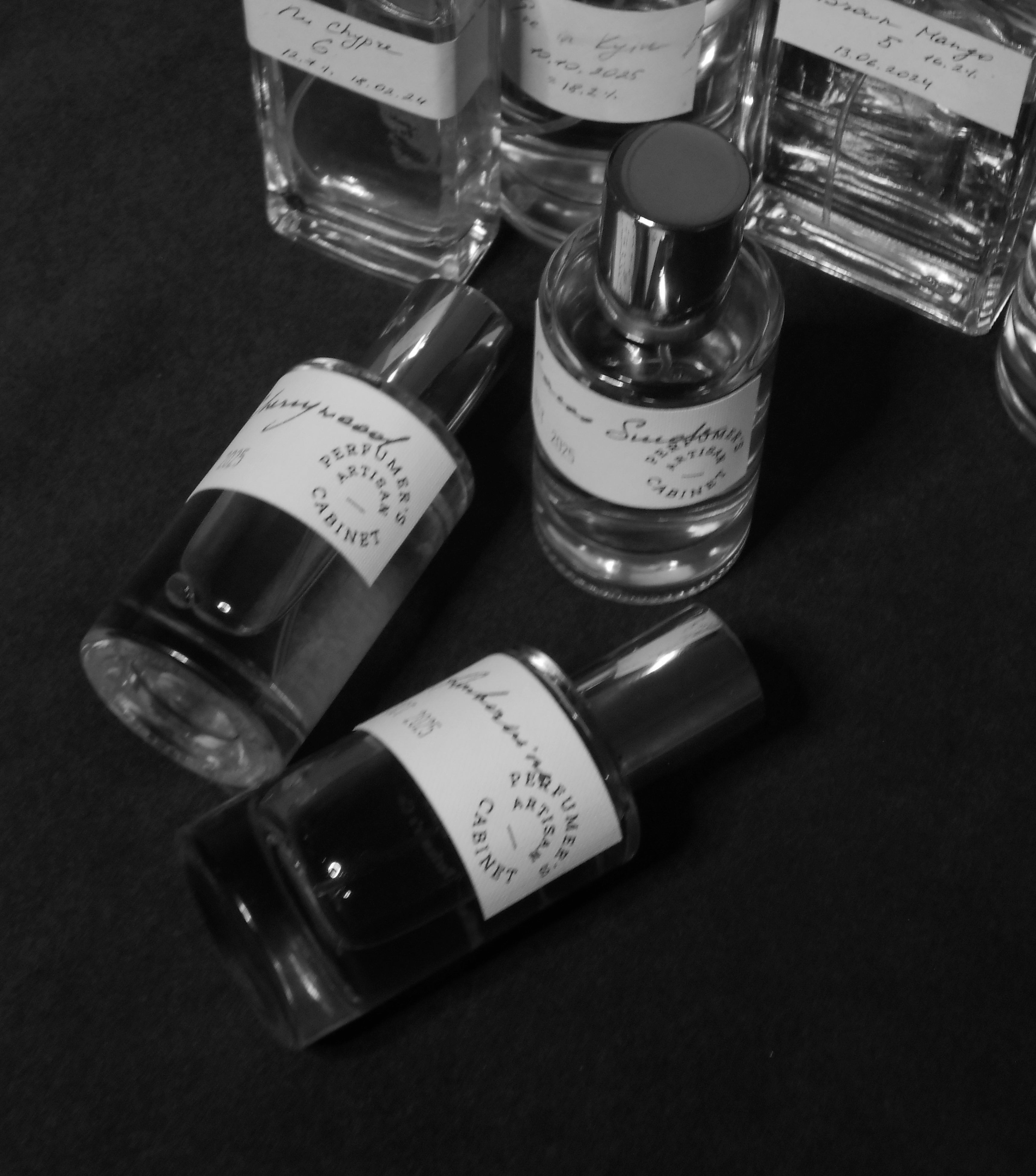 Collection of perfume bottles with labels on a dark surface